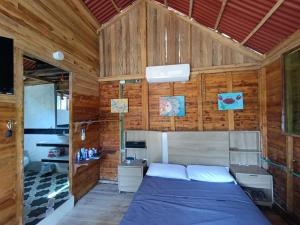 a bedroom with a bed and wooden walls at Palmar Beach Cabañas - Bahía Rada in Moñitos