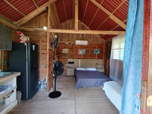a bedroom in a log cabin with a bed and a refrigerator at Palmar Beach Cabañas - Bahía Rada in Moñitos