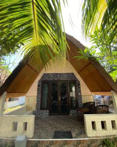a house with a palm tree in front of it at meno smile cottages 2 in Gili Meno +2 photos
