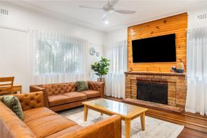 a living room with a couch and a flat screen tv at Wattleseed - 4 Wattle Street in Evans Head