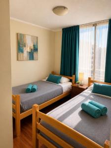 a bedroom with two beds with blue pillows on them at Departamentos Amoblados Torre Tagle in Santiago
