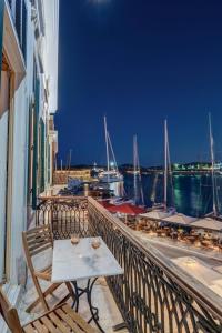 a table on a balcony with a view of a harbor at Hotel Aktaion Syros in Ermoupoli