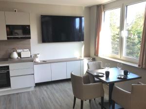 a kitchen with a table and a tv on the wall at Appartement Am Sandhuf in Lubmin +6 photos