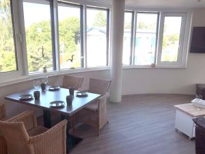 a dining room with a table and chairs and windows at Panorama Suite in Lubmin +11 photos