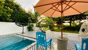 an umbrella and chairs next to a swimming pool at Sunrise Beach House 1 in Tiến Thành