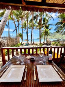 a wooden table with two plates and a bottle of wine at Beachfront Bungalows Bucana, El Nido in El Nido +9 photos