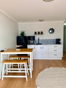 a kitchen with white cabinets and a table and chairs at Sussex View - Waterfront Couples Retreat in Sussex Inlet in Sussex Inlet