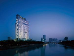 un bâtiment éclairé à côté d'une rivière la nuit dans l'établissement Shangri-La Ningbo - The Three Rivers Intersection, à Ningbo