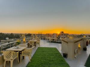 a rooftop patio with tables and chairs and a sunset at Nigmt Siwa Hotel in Siwa