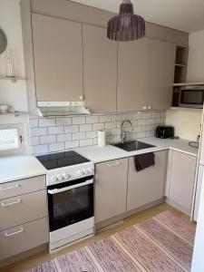 a kitchen with white cabinets and a stove and a sink at Paimenkatu 1 in Savonlinna