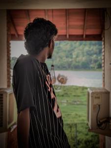 a man wearing a tie looking out of a window at Hotel Villa Lake View in Kurunegala