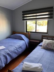 a bedroom with two beds and a window at Ventisqueros Coyhaique in Coihaique