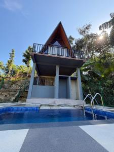 a house with a balcony next to a swimming pool at Sinharaja Kithula Eco Cabanas in Batuwangala
