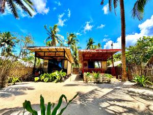 a house on a beach with palm trees in the background at Beachfront Bungalows Bucana, El Nido in El Nido