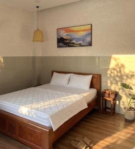 a bedroom with a bed and a painting on the wall at Nếp Nhà Homestay in Tân Phú