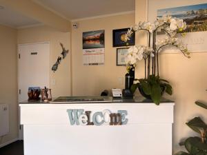 a reception desk with white flowers on top of it at Tudor Lodge Motel in Nelson