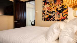 a bedroom with a white bed with a painting on the wall at Villa Agata Mauritius in Mont Choisy