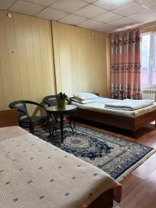 a room with two beds and a table and a window at Жетиген in Karakol +12 photos