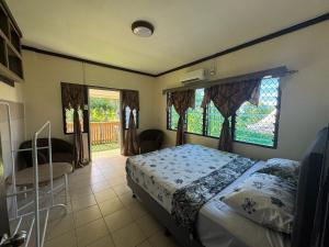 a bedroom with a bed and a chair and windows at Linas Lodge in Vaitele