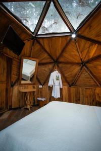 a bedroom with a bed in a wooden room with a window at Los Pinos EcoHotel in Hobo