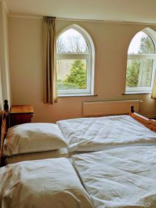 two beds in a bedroom with two windows at Karakul Shepherd House in Tinglev