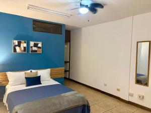 a bedroom with a bed with a blue wall at Luca in San José