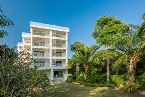 格林的住宿－羅勇府班德拉海上度假酒店，一座高大的白色建筑,前面有棕榈树
