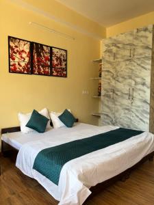 a bedroom with a large white bed with blue pillows at Aangan by Mom in Kalpa