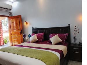 a bedroom with a large bed with purple and green pillows at Corbett Krishna Inn in Belparāo +5 photos