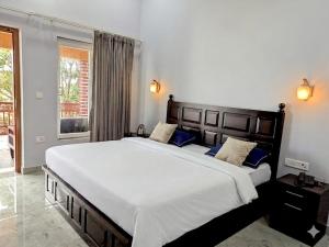 a bedroom with a large white bed with blue pillows at Corbett Krishna Inn in Belparāo