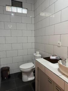 a white bathroom with a toilet and a sink at Willy Homestay in Uluwatu