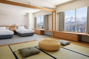 a hotel room with two beds and a large window at The Alps Hotel Hakuba in Otari