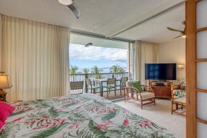 a bedroom with a bed and a balcony with a television at Mana Kai Maui Condo - Right on the Beach! in Wailea