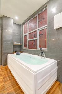a large white tub in a bathroom with windows at Hotel IVY Near Delhi Airport in New Delhi +24 photos