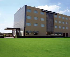 a building with a green lawn in front of it at Hotel Grand Maple in Jaipur