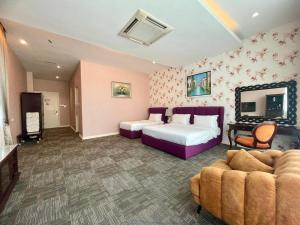 a bedroom with a bed and a couch and a tv at Casa Bianca in Kluang