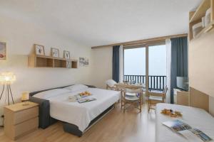 a hotel room with two beds and a table and a balcony at Studio Sansi 34 - Happy Rentals in Cesana Torinese