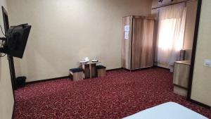 a room with a red carpeted room with two tables and a television at Sitora in Chirchiq