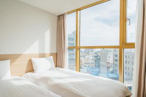 two beds in a room with a large window at Kenny Stay Jeju Seogwipo in Seogwipo