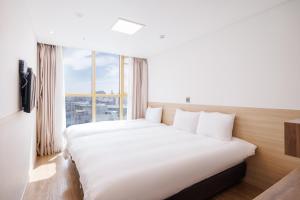 a bedroom with a large bed with a large window at Kenny Stay Jeju Seogwipo in Seogwipo