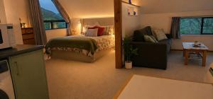 a bedroom with a bed and a couch and a chair at Hill Top Hideaway - Self Contained Guest Suite with Private Spa in Pukerua Bay