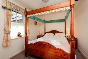 a wooden four poster bed in a bedroom with a window at Bramble Cottage in Wooler +43 photos