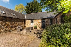 an exterior view of a stone house with a patio at Bramble Cottage in Wooler
