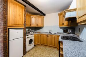 a kitchen with wooden cabinets and a washer and dryer at Fern Cottage in Wooler