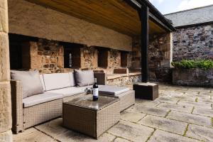 an outdoor patio with a couch and a table at Fern Cottage in Wooler