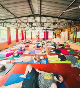 eine große Gruppe von Menschen, die in einem Raum Yoga machen in der Unterkunft Rishikesh Valley in Rishikesh