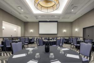 a conference room with tables and chairs and a screen at Hyatt Centric Chicago Ohare in Rosemont
