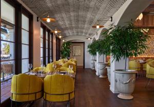 a restaurant with yellow chairs and tables and windows at Mar Monte Hotel, in The Unbound Collection by Hyatt in Santa Barbara