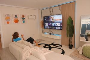 a woman sitting on a couch in a living room at Serene Mountain View Smart Apt for Restful Stays in Castries