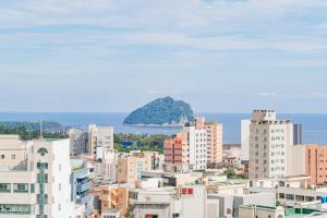 a city with buildings and an island in the distance at Kenny Stay Jeju Seogwipo in Seogwipo